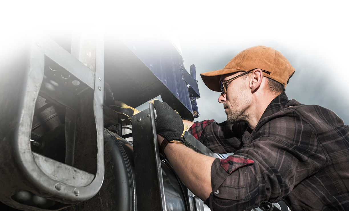 Kierowca ciężarówki w wieku 40 lat sprawdza elementy pojazdu w pobliżu zbiornika paliwa. Temat transportu ciężkiego.