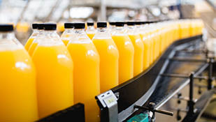 Usine d'embouteillage - Ligne d'embouteillage de jus d'orange pour le traitement et l'embouteillage du jus en bouteilles. Mise au point sélective.